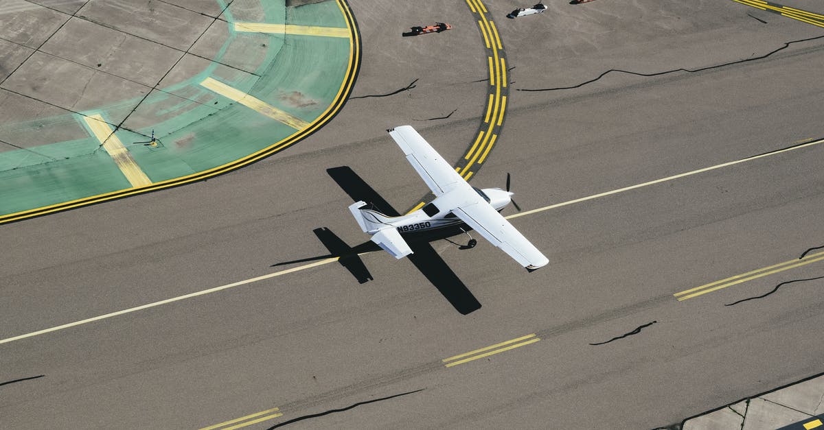 Book a flight from CDG Airport - From above of small biplane landing on runway with cracks and yellow markings on summer sunny day