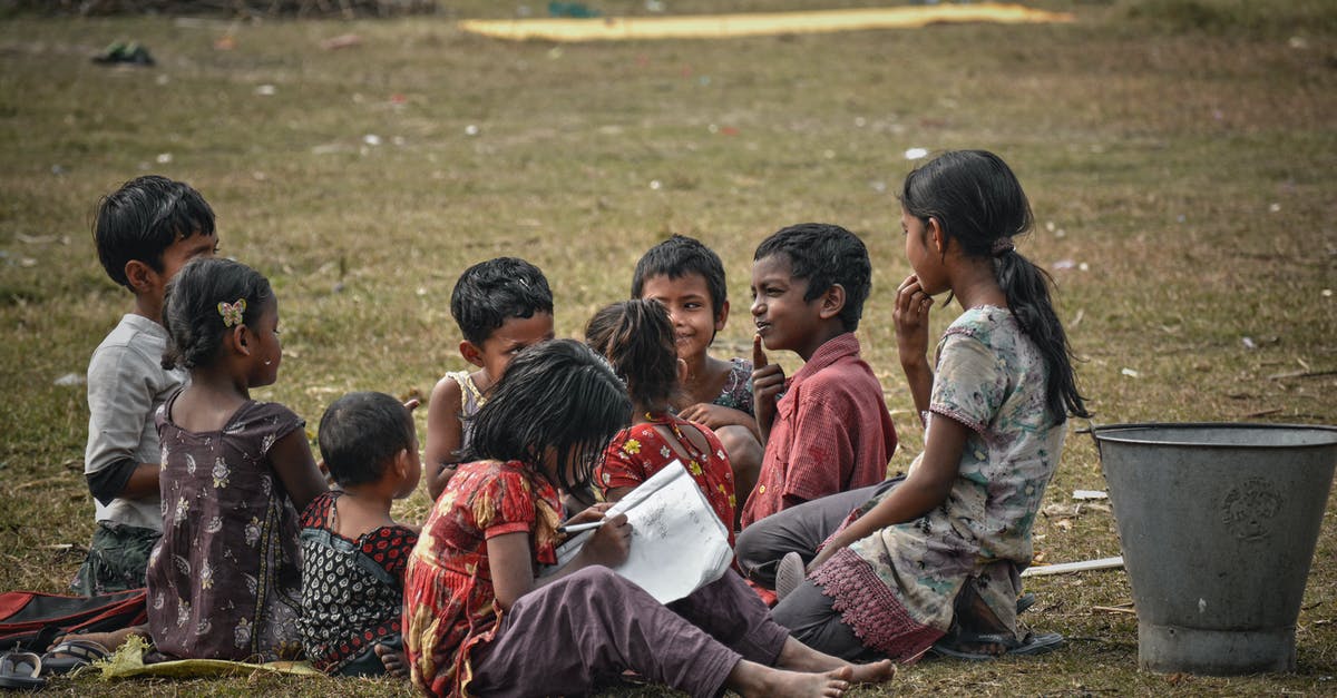 Booking 1A berth with a child on Indian Railways - Group of full body ethnic children sitting on lawn and spending time together while unrecognizable little girl diligently doing homework wring in sheet of paper on street