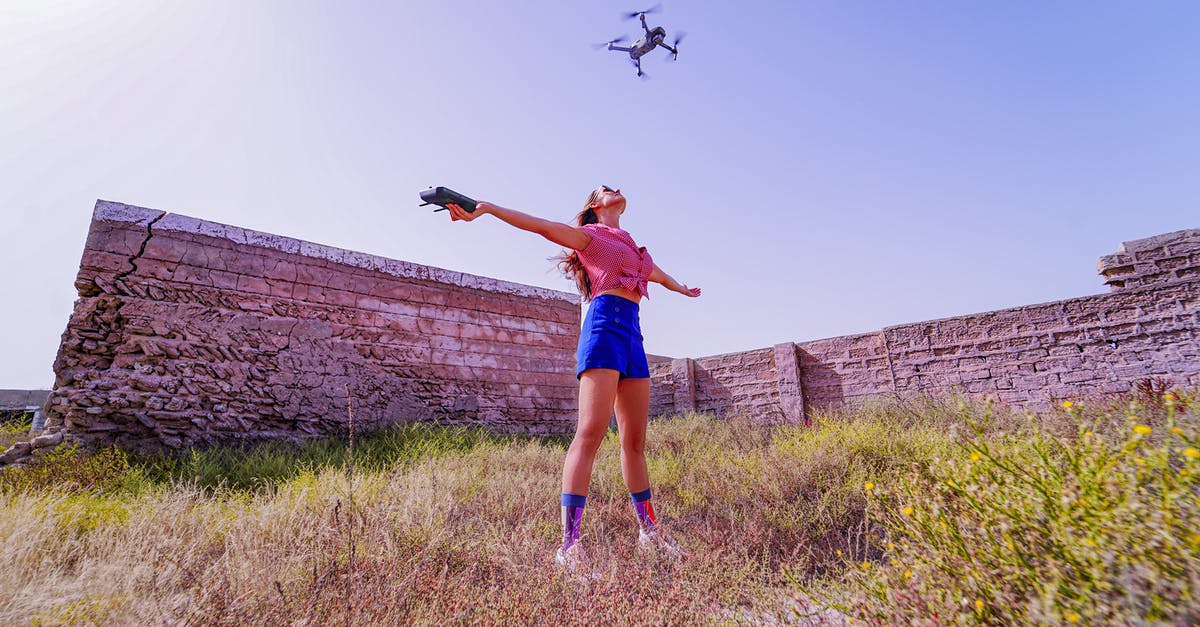 Booking a backup flight for short layover - Fit woman standing with arms outstretched under flying drone