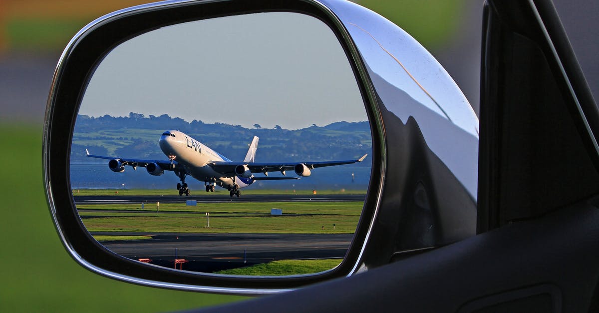 Booking a flight in the airport right before departure - White Airplane Reflection on Car Side Mirror