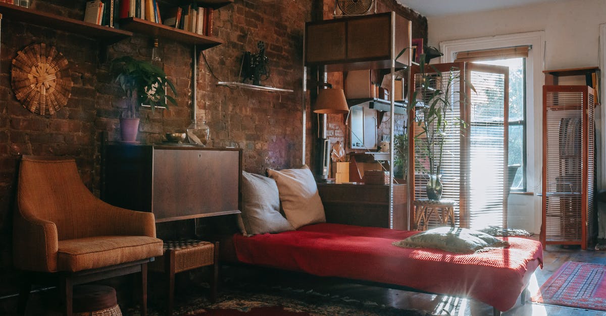 Booking accommodation for long term (few months) - Vintage styled bedroom interior with classic wooden furniture and bookshelves decorated weathered brick wall near comfortable bed and armchair