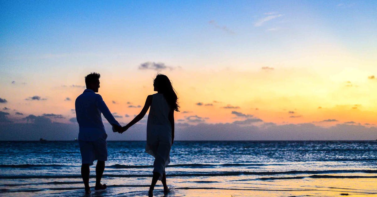 Booking honeymoon before name change [duplicate] - Man and Woman Holding Hands Walking on Seashore during Sunrise