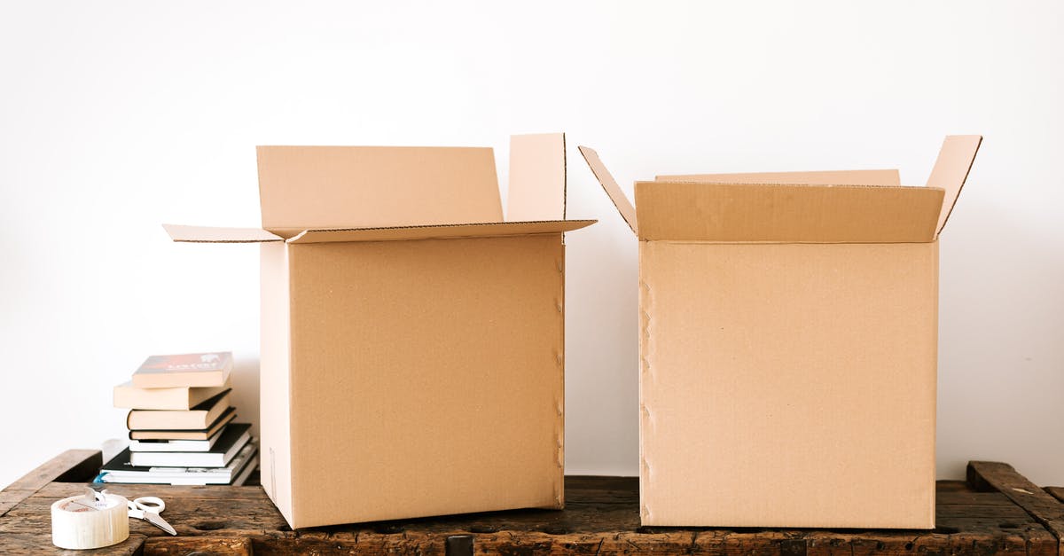 Booking last minute accommodation in Ireland - Opened carton boxes and stacked books placed on shabby wooden desk with tape against white wall