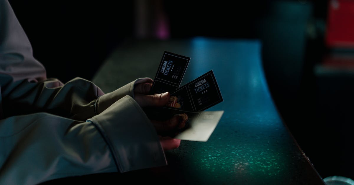 Booking tickets separately - Selective Focus Photo of a Person Holding Three Cinema Tickets