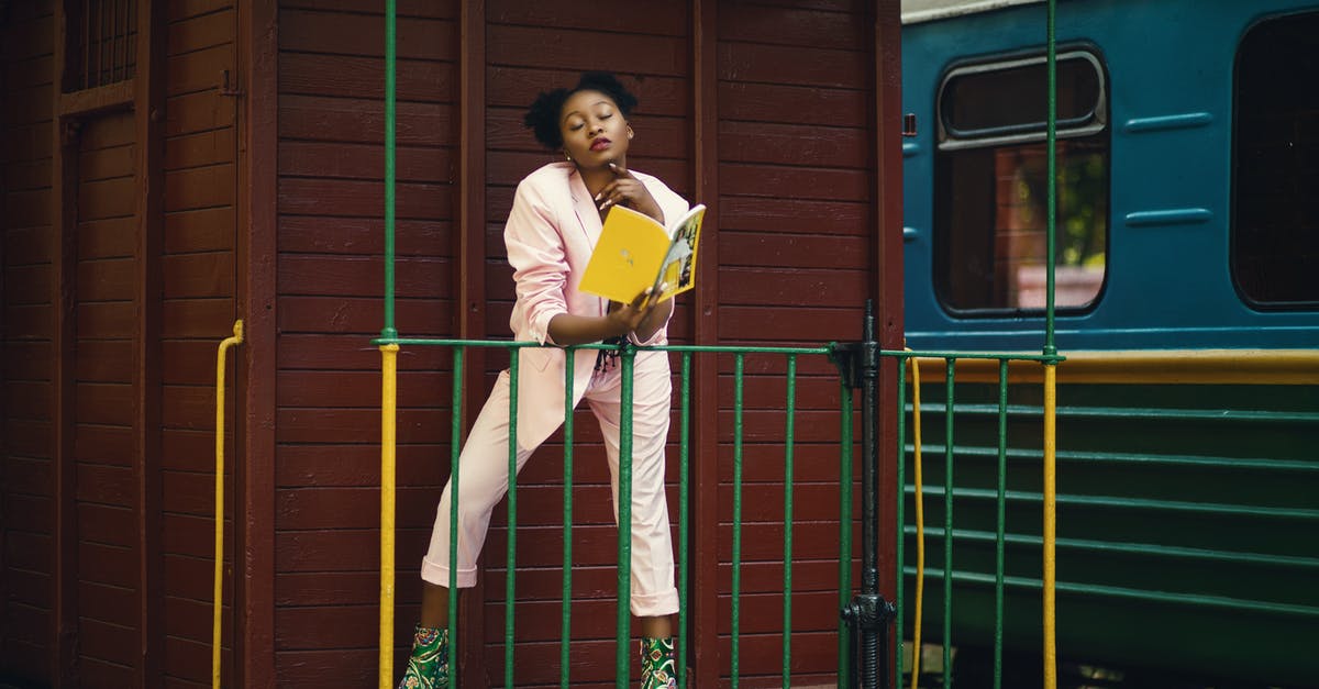 Booking train tickets on RENFE site - Woman Wearing Pink Blazer, Pants and Green Heeled Shoes Holding Yellow Covered Book