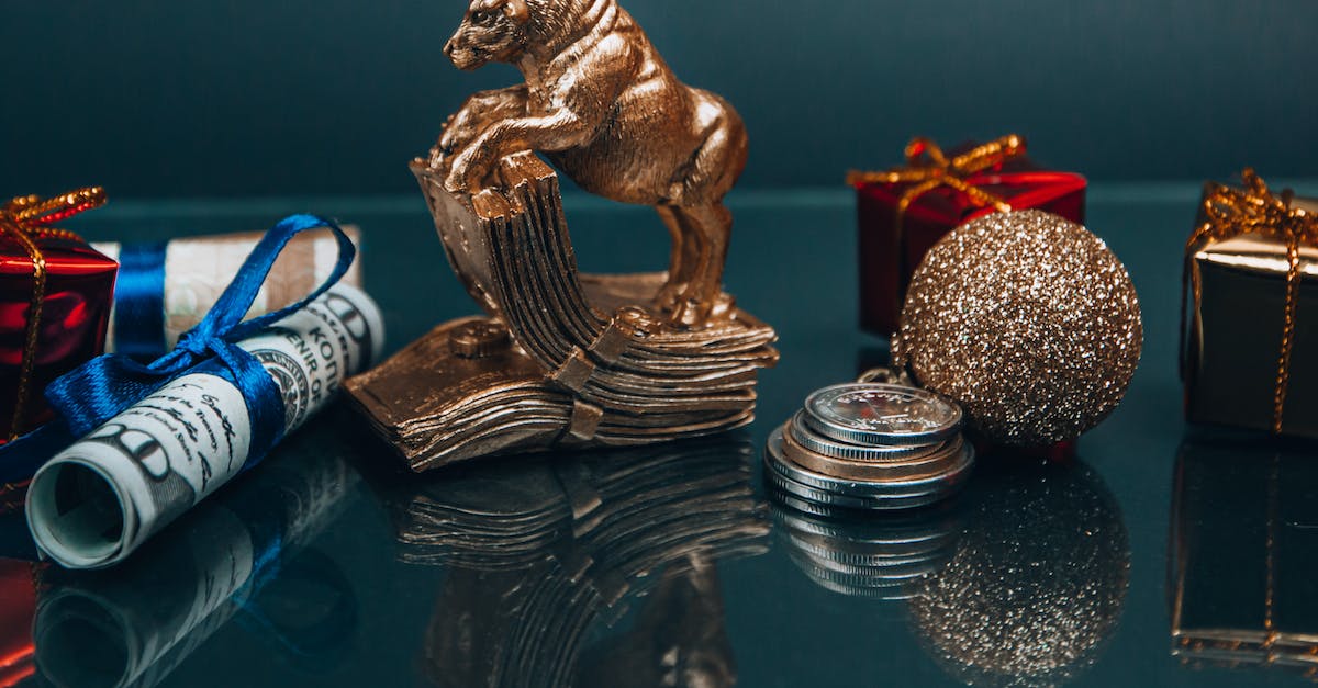 Boracay over Chinese New Year - High angle composition of Ox year symbol figurine and wrapped presents placed on mirrored table with coins and rolled and tied dollar banknotes