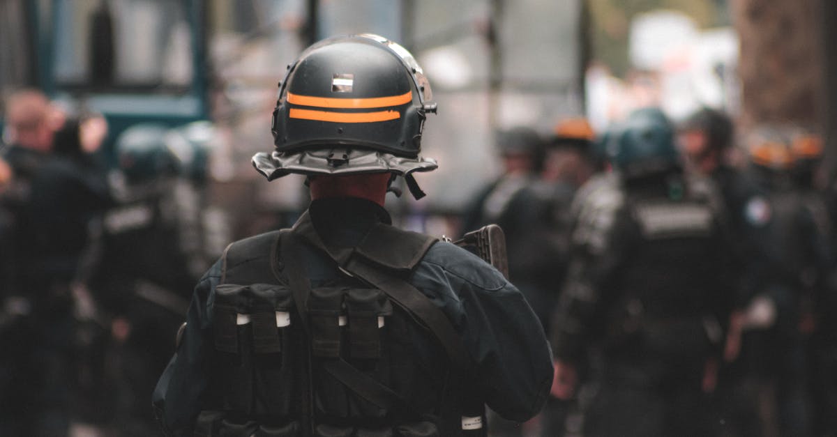 Border control officer asking questions on leaving Canada - Back view of anonymous policeman in helmet and bulletproof vest maintaining law and order while standing on city street