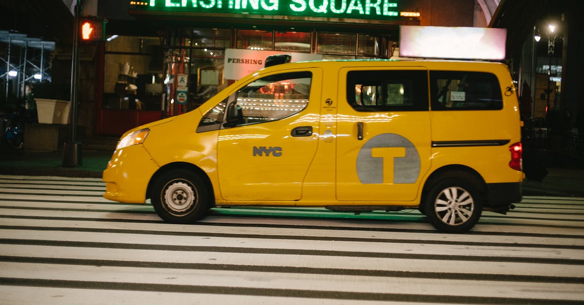 Boro cab service in New York City - Shiny yellow van taxi parked on street near entrance of cafe with neon sign in New York at night