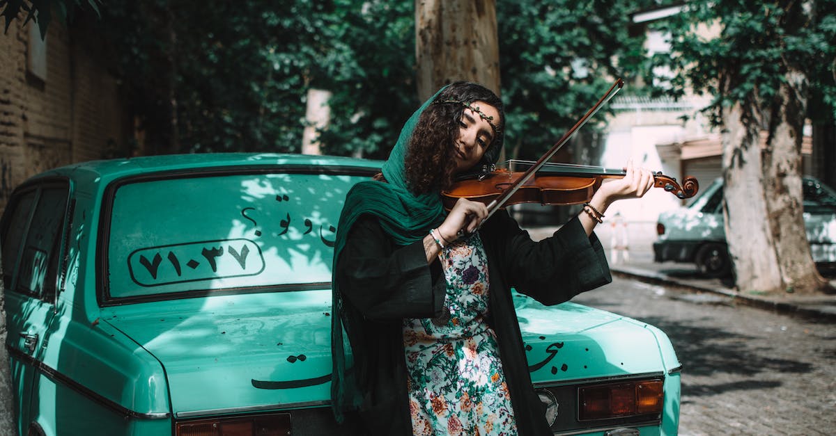 Breast feeding in Iran - Woman Playing Violin While Leaning On Green Vehicle