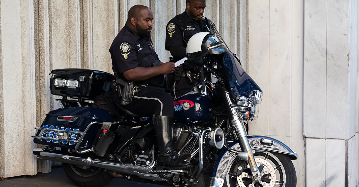 Bribing Indonesian police for missing motorbike license - Standing Police Man Beside Another Man Who Seats of Police Motorcycle