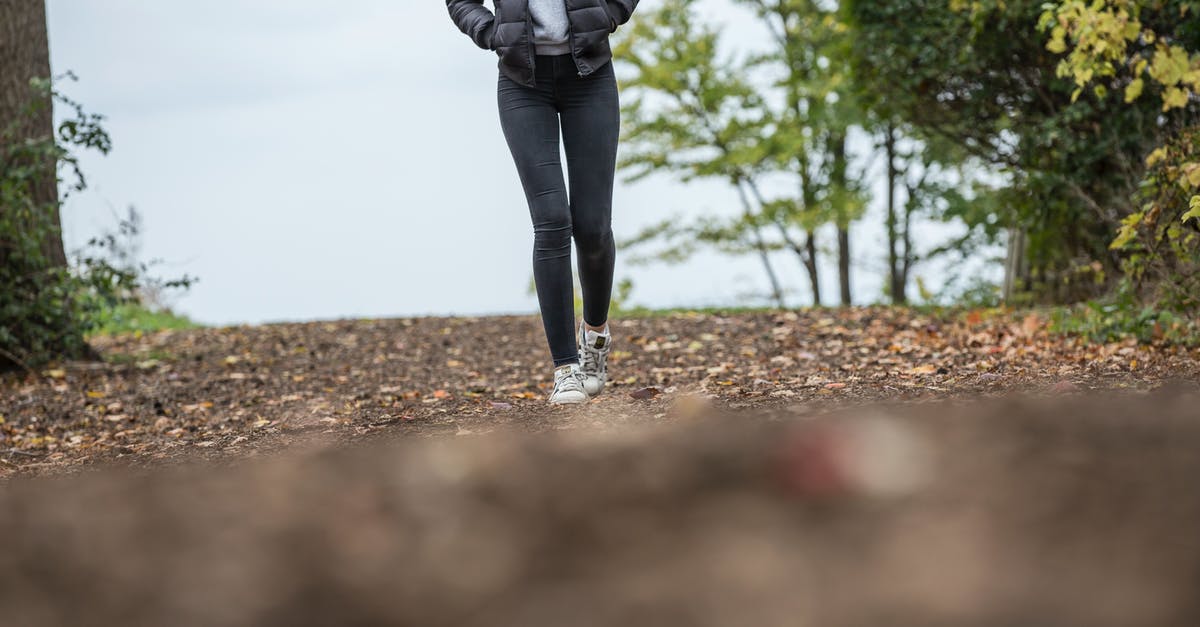 Bringing hiking shoes with dirt/soil to the US? - Woman in Black Leggings While Walking on Brown Road