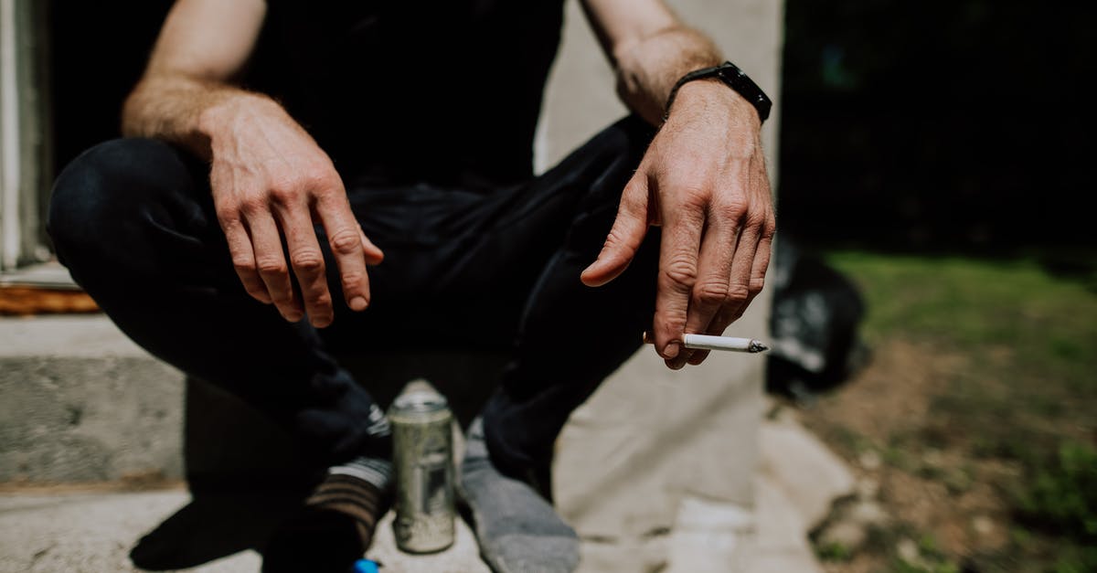 Bringing nicotine e-liquids to Australia - Crop man sitting on steps with cigarette in hand