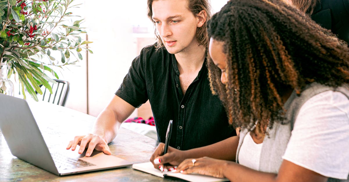 Bringing present to a culture interview meeting in Germany? - Man Working on Laptop while Woman Takes Notes