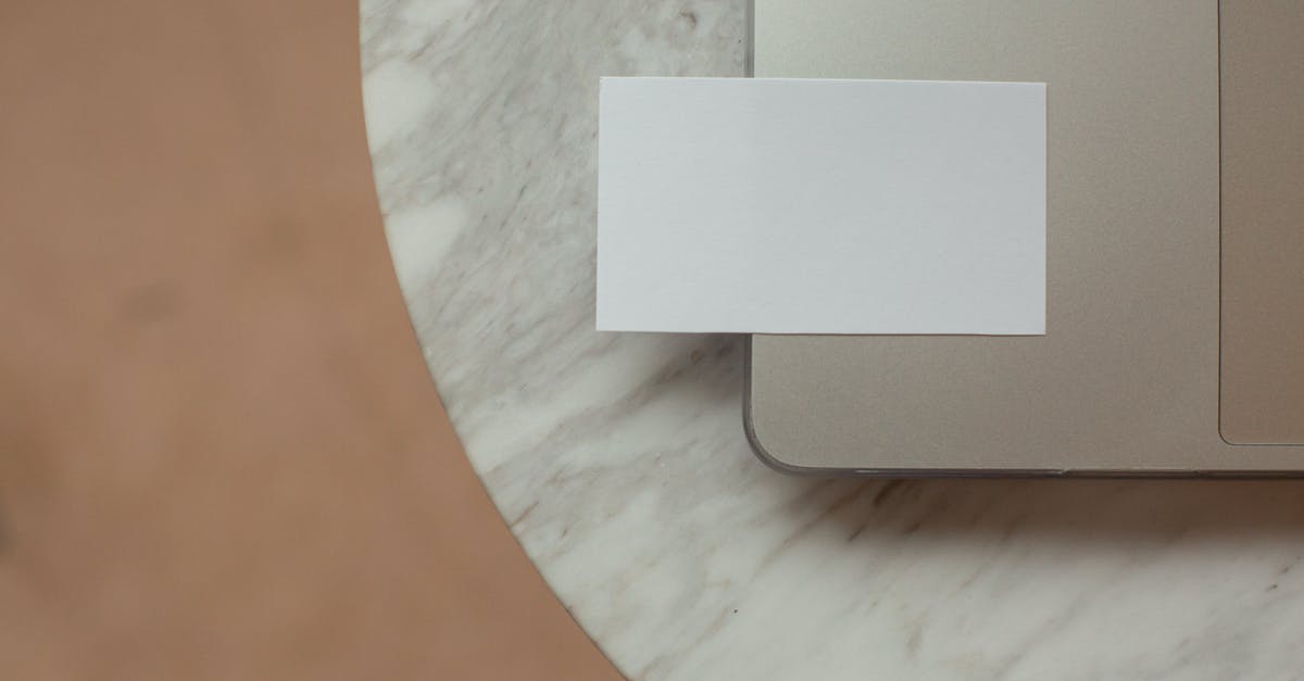 Bringing Siblings as a Blue Card Holder - Top view white mock up business card with copy space placed on modern opened netbook on round marble table in light room