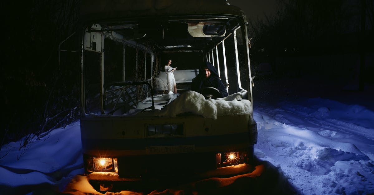 Bus 965 to Jiufen - A Man in Black Hoodie Sitting on a Damaged Bus on Snow Covered Ground