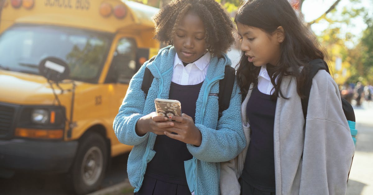 Bus connection from Jesenik to Vidnava, Czech Republic - Diverse schoolgirls surfing smartphone on sunny street