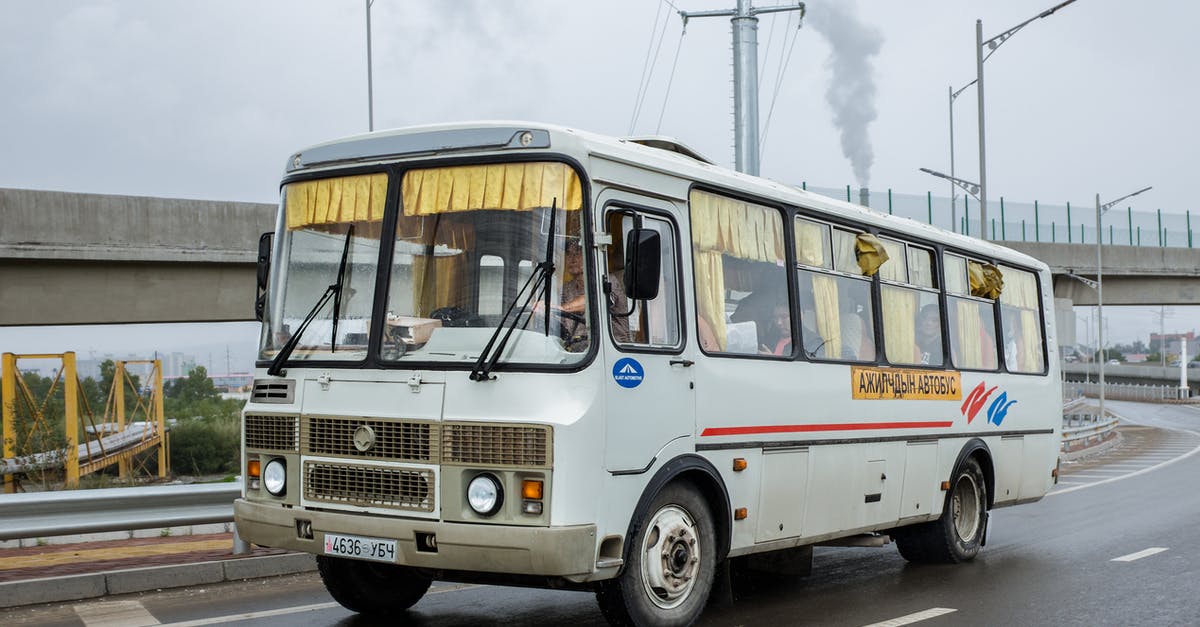 Bus line 21 from Nice to Castellane - Local public bus with anonymous driver and passengers windshield driving on asphalt road with marking lines near cement bridge under cloudy sky with smoke