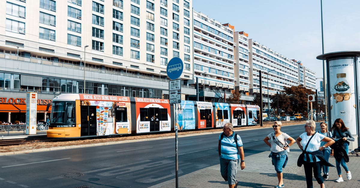 Bus search engines for Germany without place of arrival? - People Walking on Sidewalk Near White Concrete Building