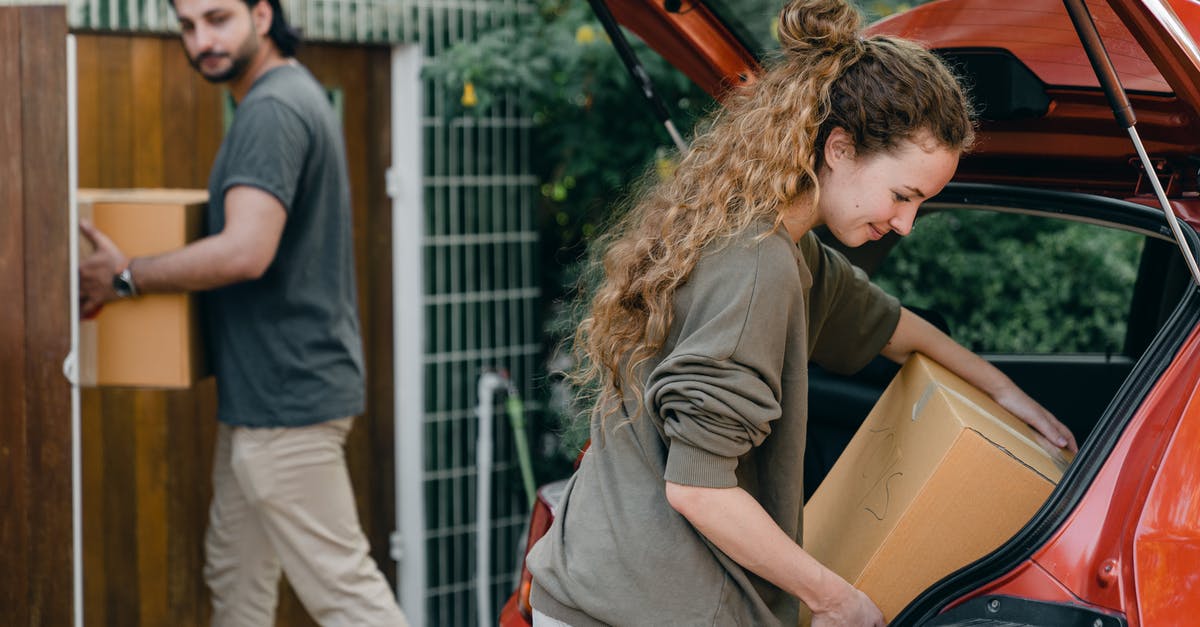 Busch Gardens Williamsburg VA without a car - Multiethnic young couple in casual wear taking carton boxes out of automobile trunk near newly bought house on summer day