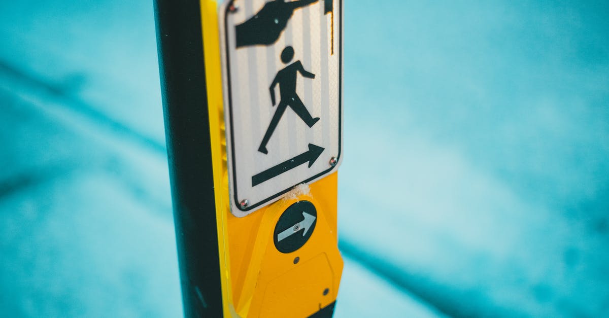 Button for pedestrian traffic lights in Germany - Selective focus of blind and deaf friendly pedestrian crosswalk control button for changing traffic lights and crossing street on zebra in traffic with sign on street