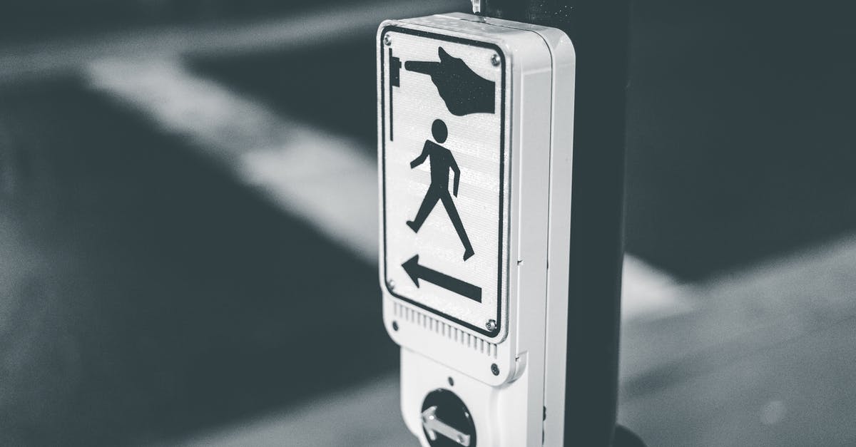 Button for pedestrian traffic lights in Germany - Black and white of pedestrian crosswalk call button placed on city street against asphalt road in evening time