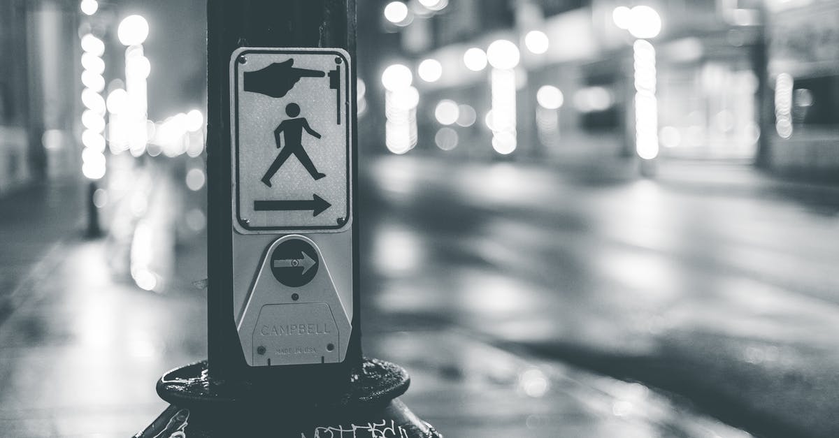 Button for pedestrian traffic lights in Germany - Pedestrian crosswalk button placed near roadway in city in evening time