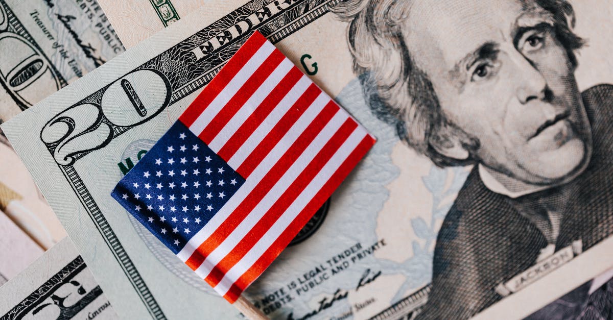 Buy smartphone in US while visiting, fees in Europe - From above of small American flag placed on stack of 20 dollar bills as national currency for business financial operations