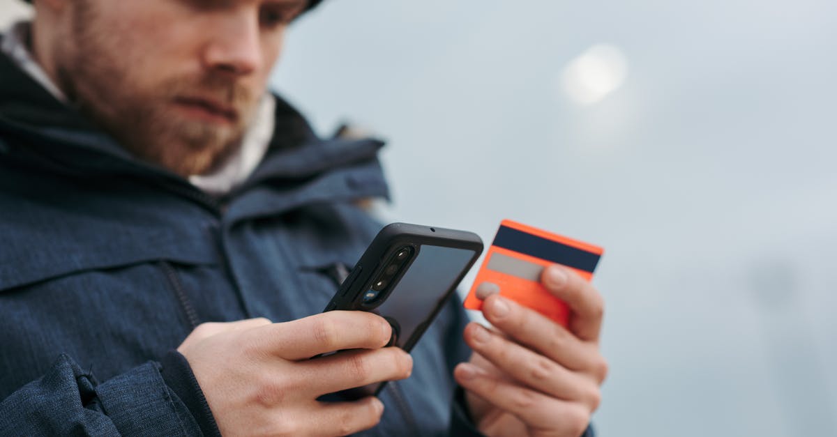 Buying a phone for using in both France and Canada - Serious man paying online purchases using smartphone on street