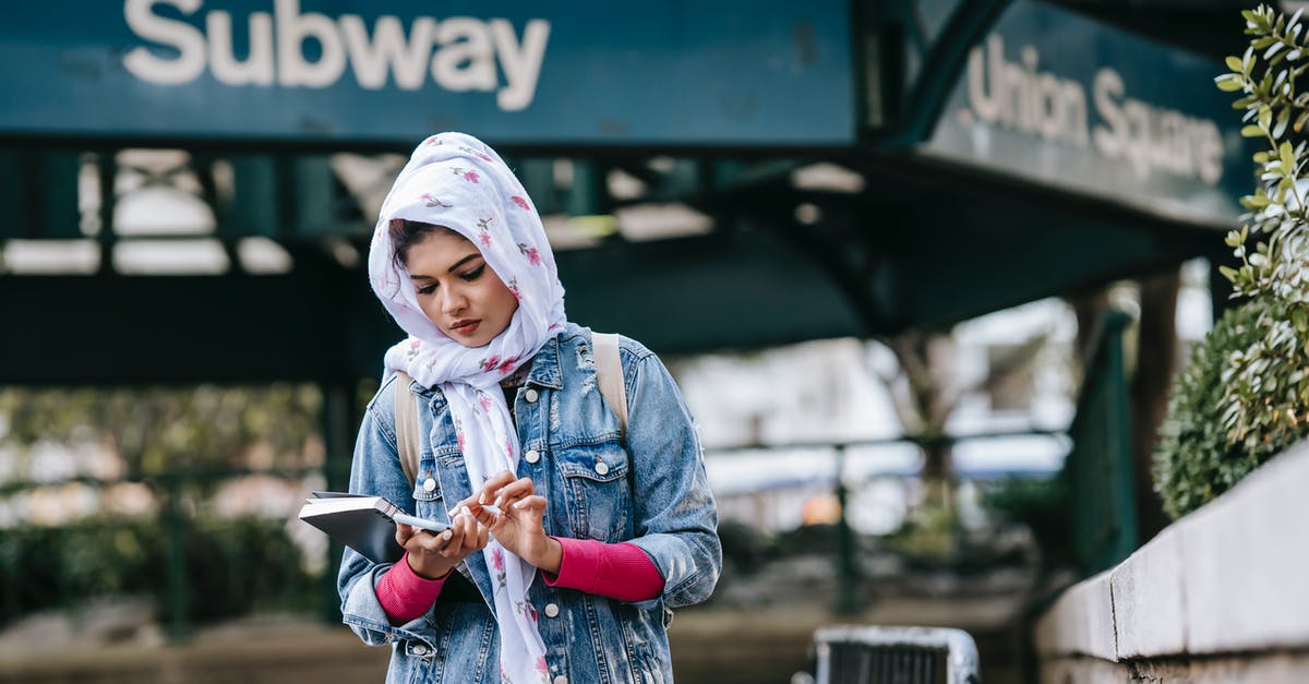 Buying a phone in the US - Serious ethnic woman messaging via smartphone while standing near subway