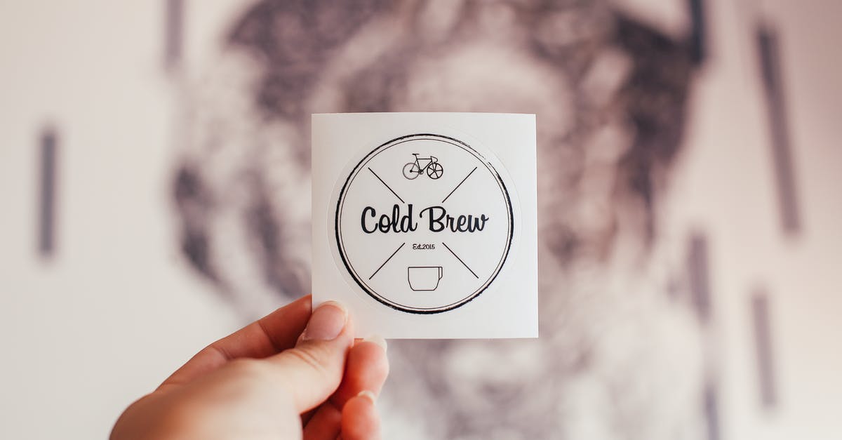 Buying Crit'air environment badge at short notice - Unrecognizable person demonstrating coffee shop badge with Cold Brew inscription and creative design in hand while standing on blurred background