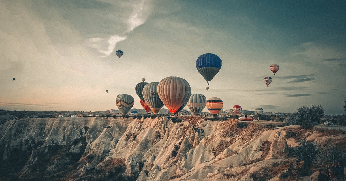 Buying flight ticket but in different situation - Assorted air balloons flying above sandy mountains