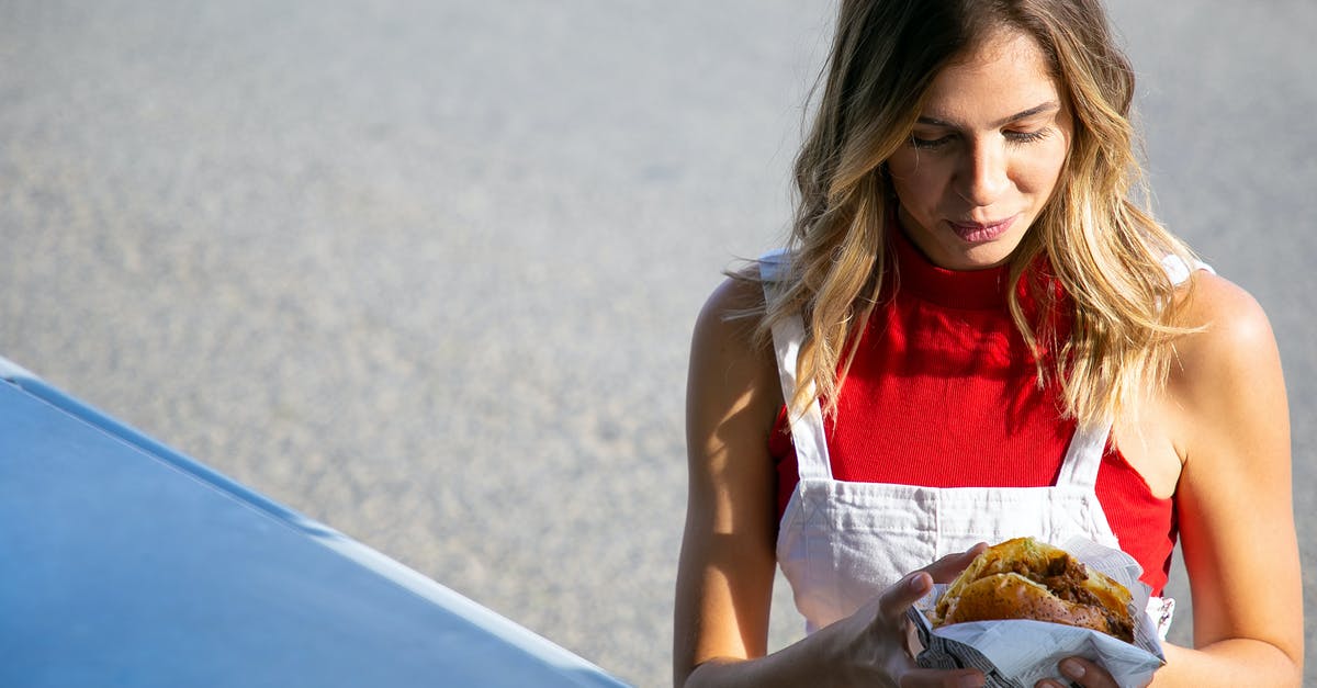 Buying reindeer meat in Helsinki - Young woman with hamburger on street