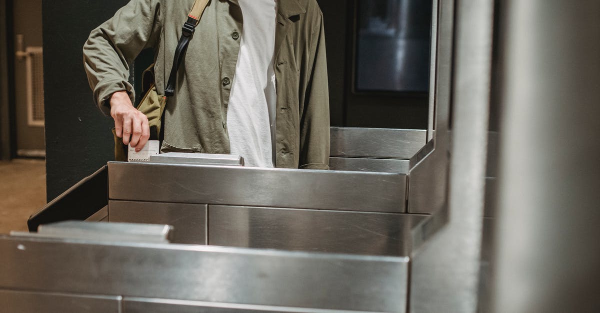 Buying ticket on Russian train - Crop unrecognizable male passenger in casual clothes with backpack inserting ticket in entrance machine of automated gate while entering modern subway station