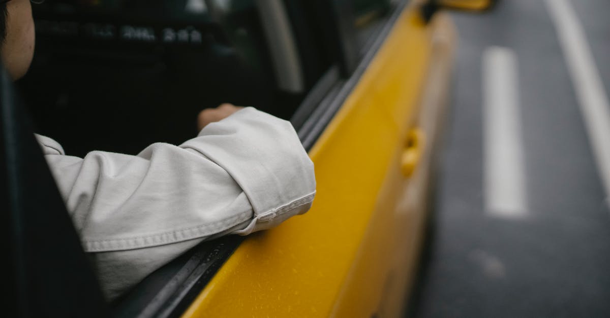 Cab company in Boston with child car seats? - Unrecognizable man in shirt and eyeglasses sitting in yellow cab while looking away in soft daylight