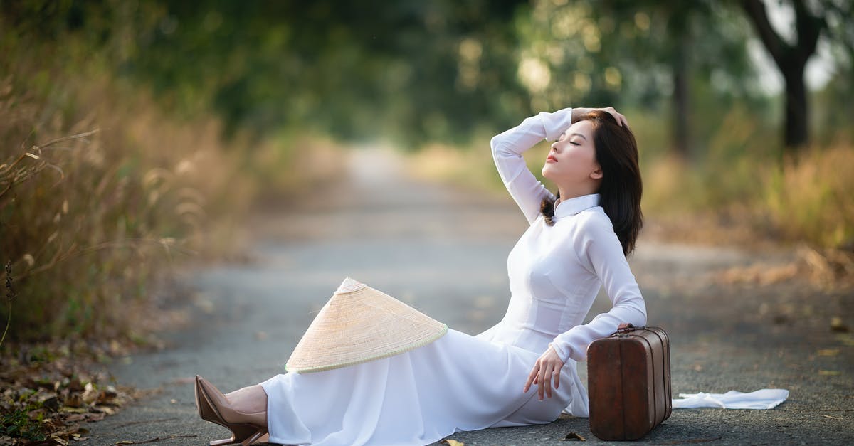 Cabin bag total linear length is 125 [closed] - Side view of calm Asian female in white dress sitting with closed eyes on asphalt walkway and leaning on suitcase in park in daytime