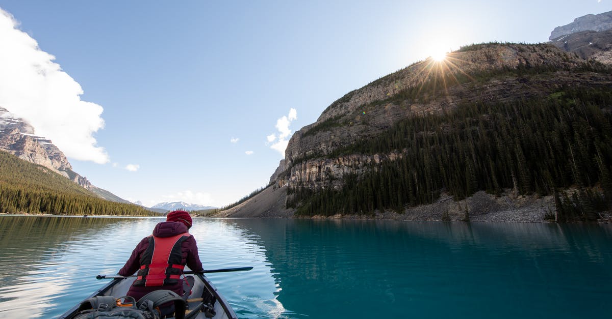 Camping in French National Parks - Person Riding Boat in Body of Water Between Islands