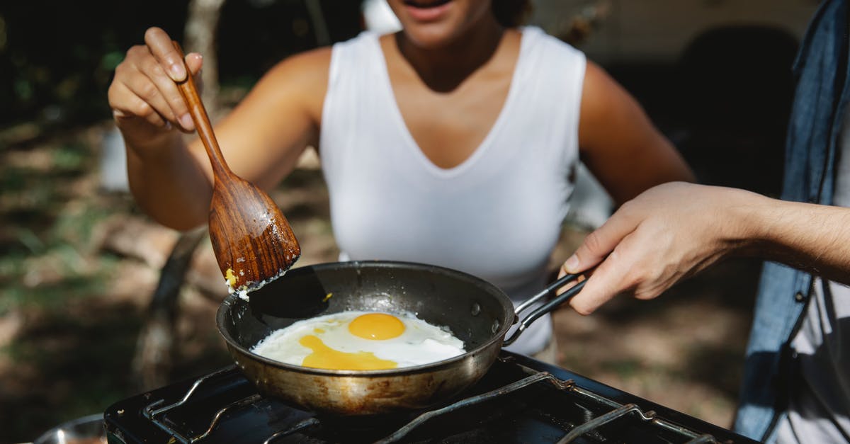 Camping stove on a plane? - Crop diverse couple cooking eggs on skillet