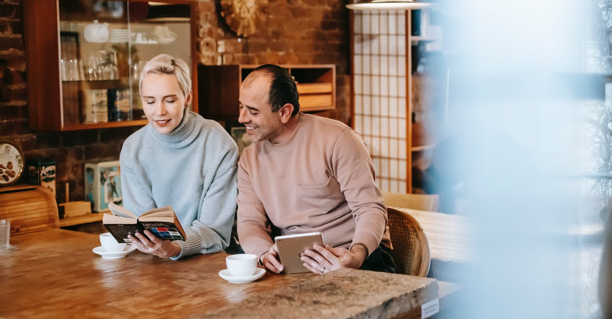 Can't book company reserved seats for spouse [closed] - Woman reading book for ethnic husband browsing tablet at table