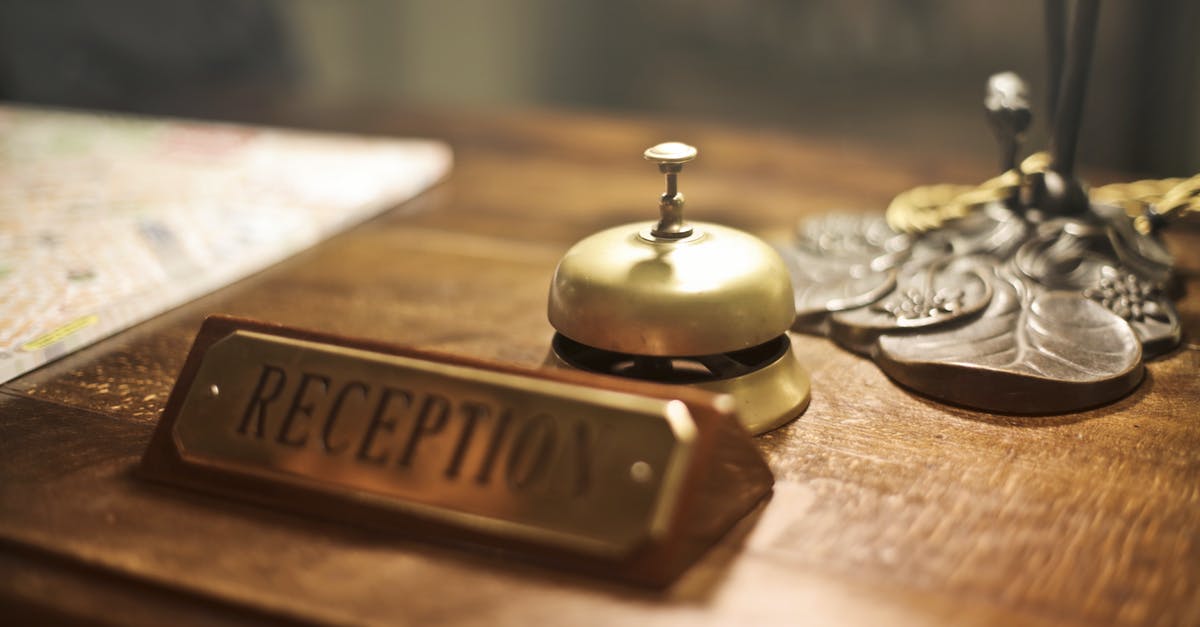 Can't check-in to a hotel because I am 18 - Old fashioned golden service bell and reception sign placed on wooden counter of hotel with retro interior