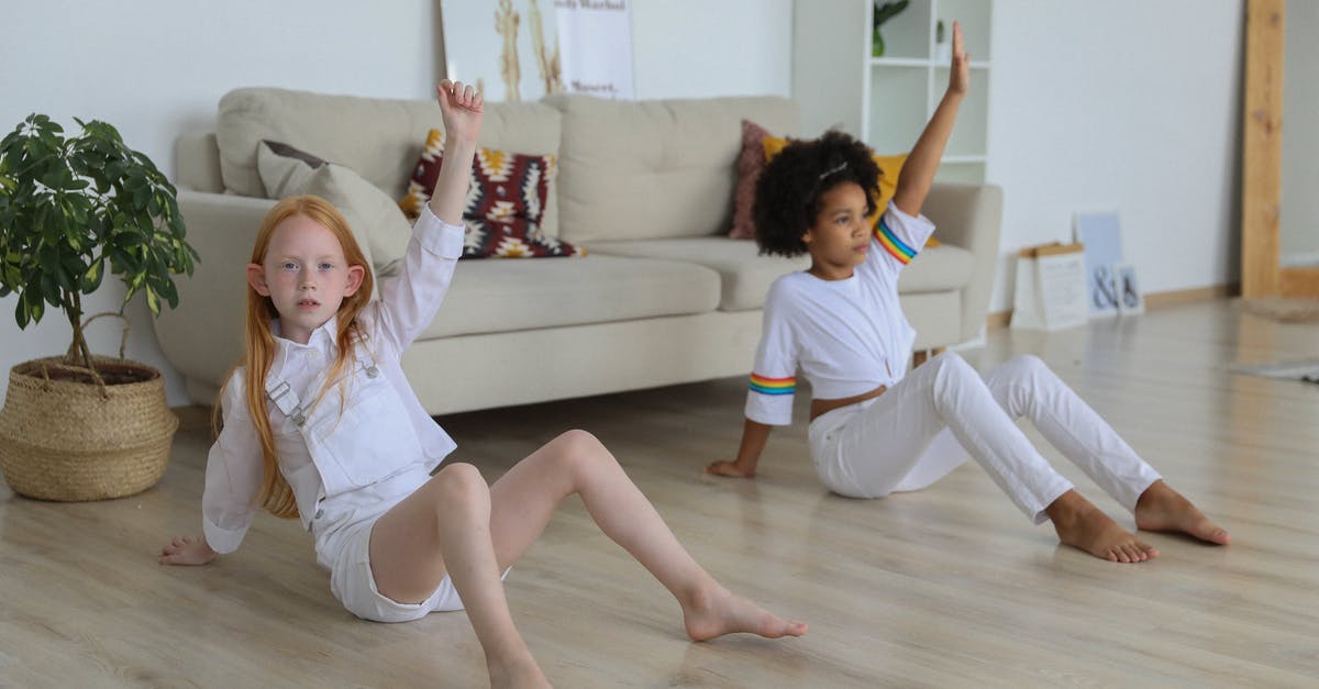 Can a child still visit the cockpit during flight? - Full body multiracial little girls sitting on floor in apartment and raising arms while training