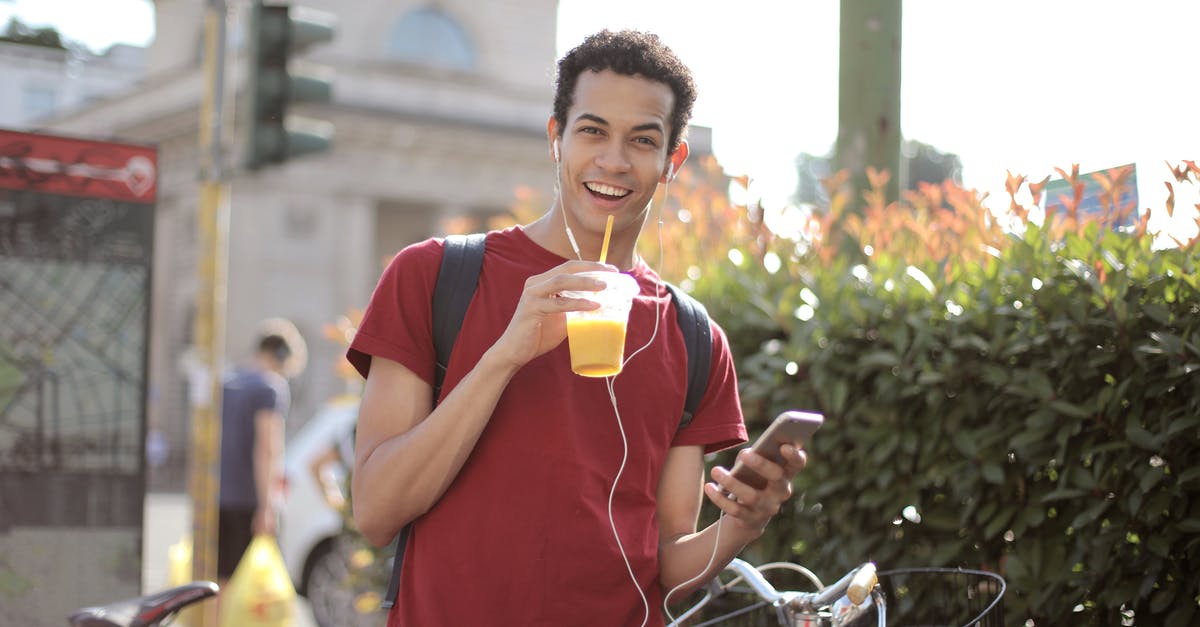 Can a F1 student go to Dominican Republic? - Happy young man using smartphone on street