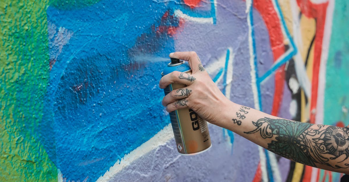 Can a husband/wife apply for UK Visas with different validities? - Crop unrecognizable tattooed painter spraying blue paint from can on multicolored wall with creative graffiti while standing on street in city