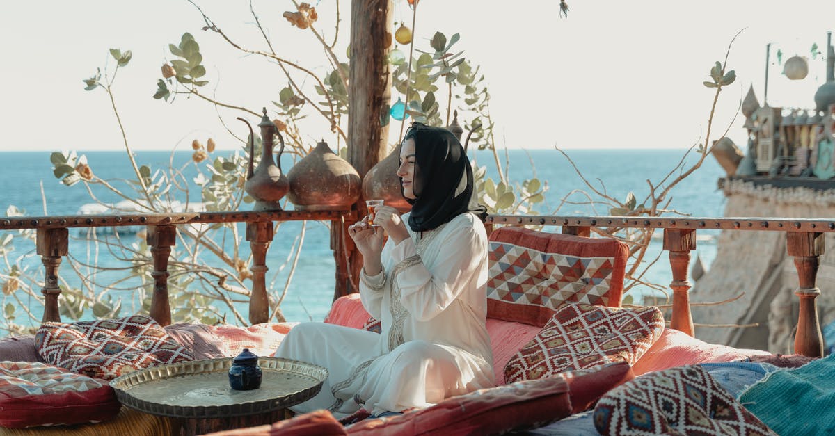 Can a Muslim woman visit Medina Mosques as tourist independently? - Woman in White Abaya And Black Hijab Sitting With View Of The Sea