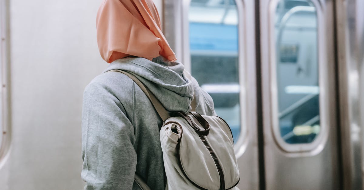 Can a non-EU citizen with an EU citizen spouse use the "EU citizen only" lane when travelling alone? - Back view of faceless Muslim woman in casual outfit with backpack and hijab standing near train in metro station