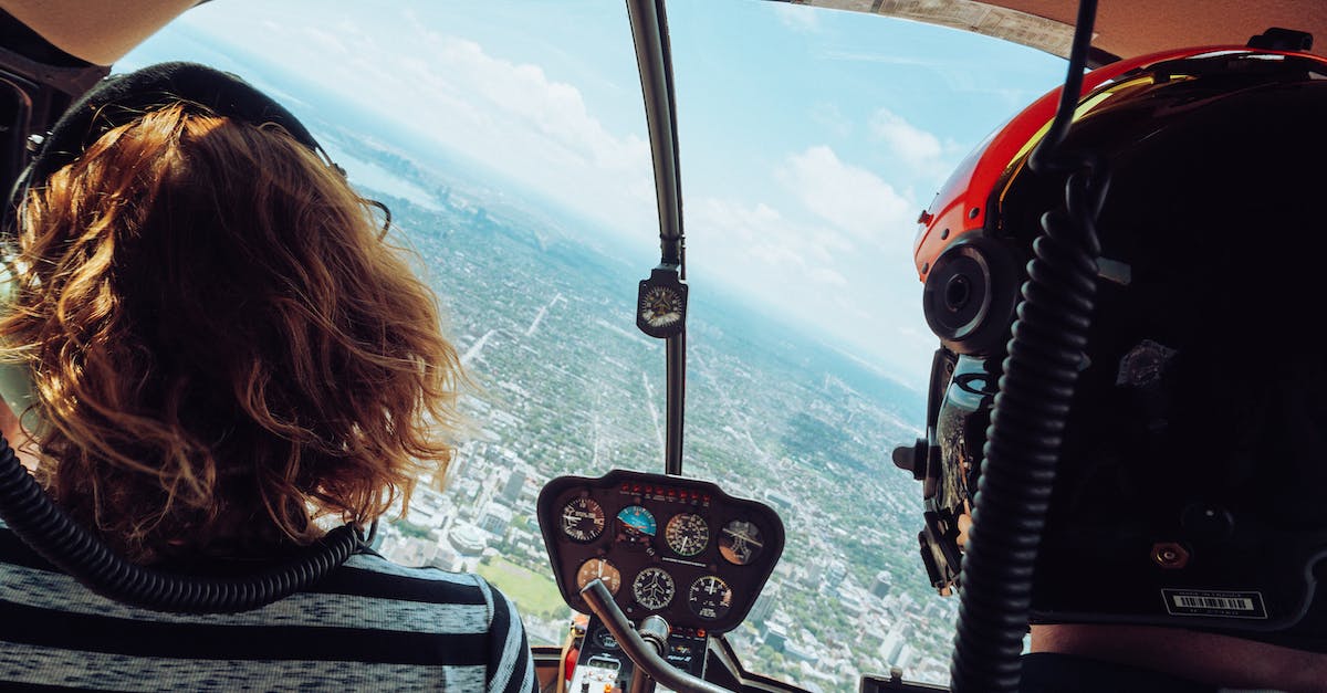 Can a person fly to the Moon as a tourist? - Back view of unrecognizable travelers in headsets admiring view of city during flight in helicopter