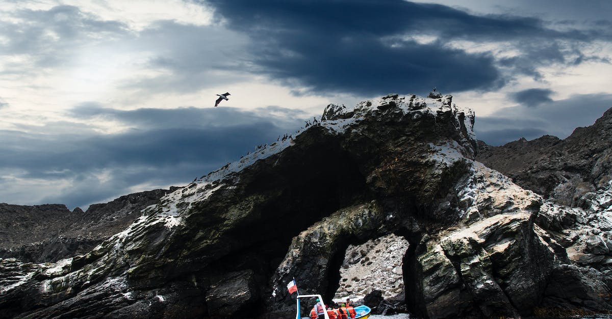 Can a person fly to the Moon as a tourist? - Back view of anonymous tourists in motor boat sailing on rippled lake between rough rocks under cloudy sky with flying bird