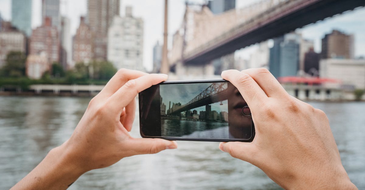 Can a tourist take part in the annual carnaval parade in Rio de Janeiro? - Crop unrecognizable traveler taking photo of modern suspension bridge in city using mobile phone in daytime