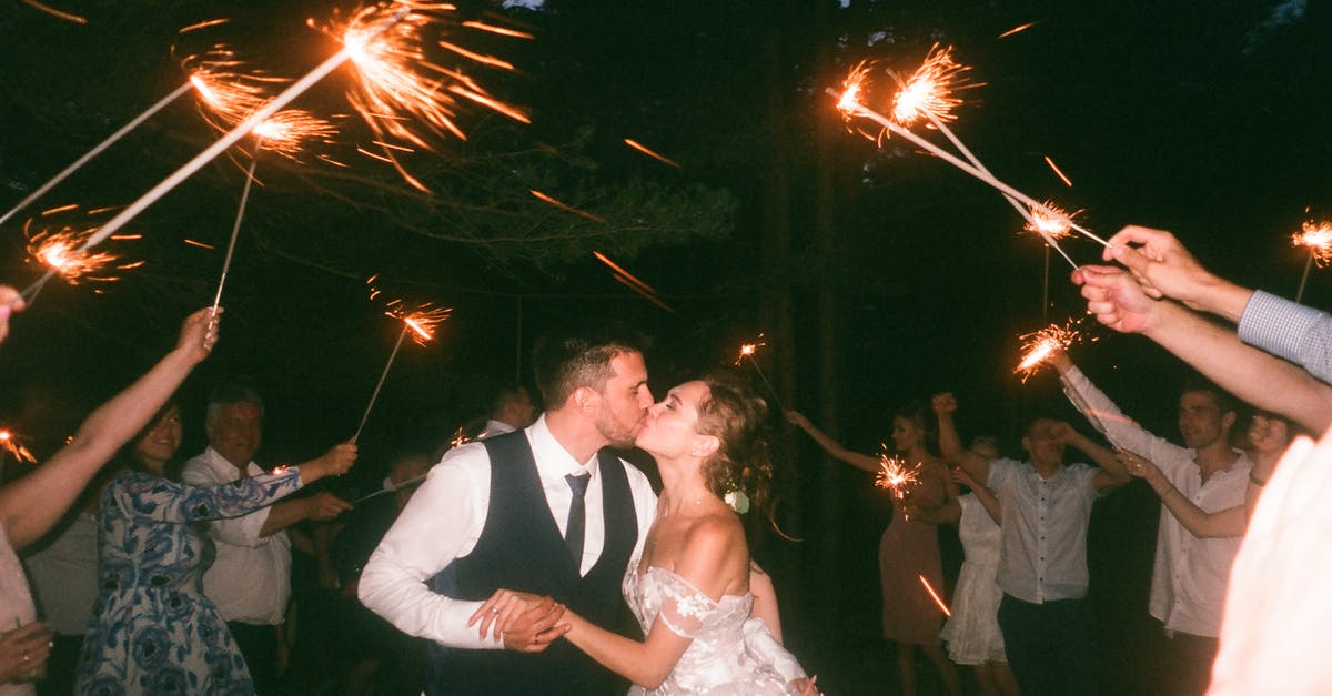 Can a transnational marriage be performed over international waters? - People Raising Lit Sparklers While Encircling Bride and Groom Kissing