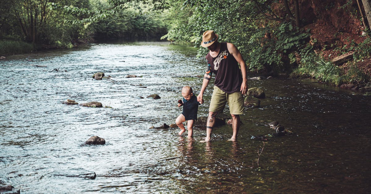 Can an infant travel anywhere on a parent's passport? - Photo of Man Holding His Child While Walking in the River