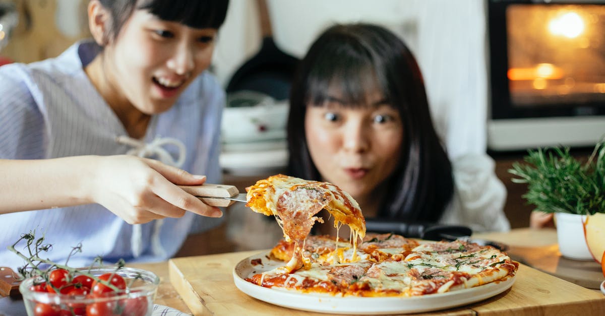 Can an Iranian with Italian residence enter Bulgaria visa free? [duplicate] - Crop delightful Asian ladies smiling while cutting piece of delicious homemade pizza with stretched cheese on cutting board in kitchen